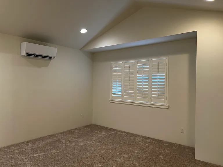 Primary bedroom with vaulted ceilings, plantation shutters, ductless heat and AC, new paint and carpet
