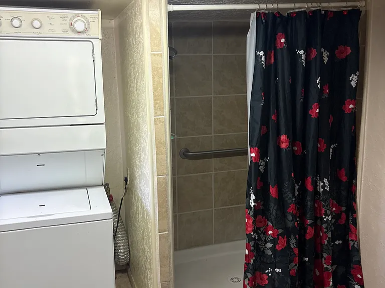 Tiled walk in shower - stacking washer and dryer