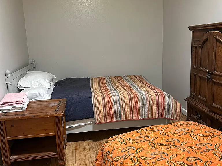 Furnished bedroom with two beds, hardwood flooring, and a dresser for convenient storage and everyday comfort.