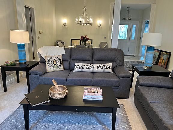 Living room looking onto attached dining area and spacious and welcoming front entry with tiled floor. The guest wing is visible to the right. The small hallway with door that leads to separate and private master suite is visible to the left.