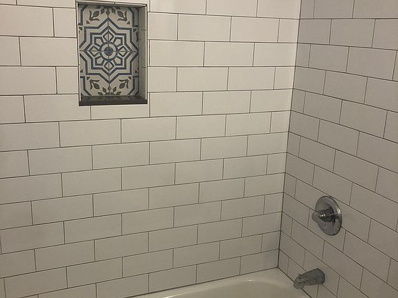Newly updated bathroom with decorative tile floor, subway tile shower, and new vanity and mirror.