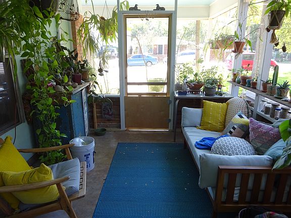Screened-in carport w/ceiling fan. Ample shelving for plants along the side. Front door has attached dog gate that can be removed.