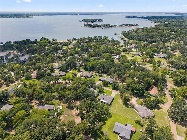 Lakefront community featuring a calm body of water, extensive tree cover, multiple residential properties, and private boat docks