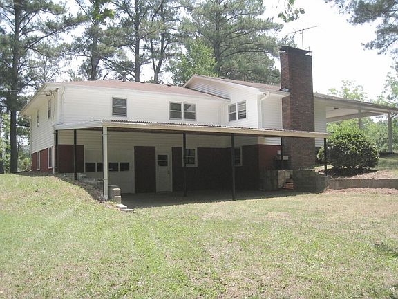 Back side of house showing basement area with covered concrete patio. A wooden privacy fence (with door) the width of patio now divides the chimney side of house from the lower level (photo not available).