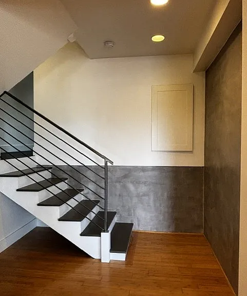 Stairs to the upper level where you will find the bathroom and bedroom. Walls are custom cement and custom metal railing. Storage space is behind the door in the wall.