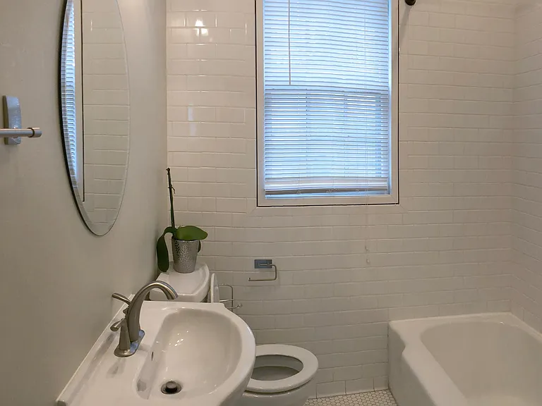 Bathroom with tiled floor and floor to ceiling subway tile .