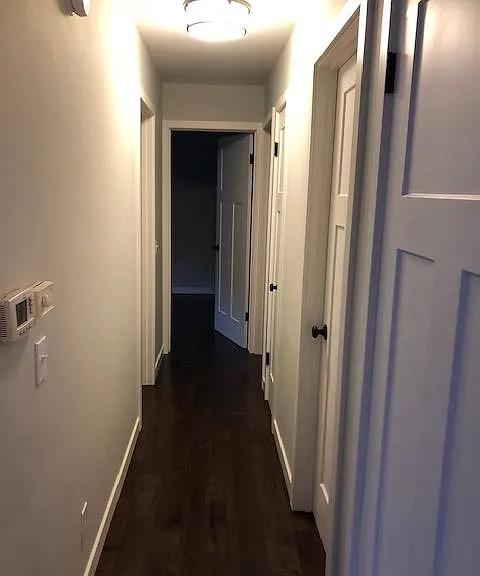 Hallway from kitchen/living space to bedrooms and bathrooms. Coat closet on the right.
