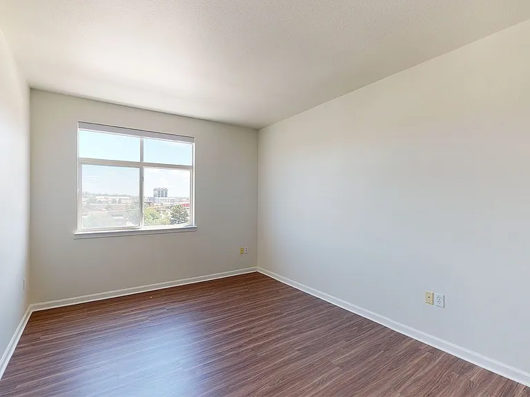 Spacious apartment bedroom with wood-style flooring.