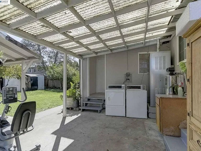 fully fenced backyard, with washer and dryer on covered patio