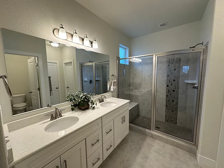 Primary bath with double sinks and sit-down tile bench in shower