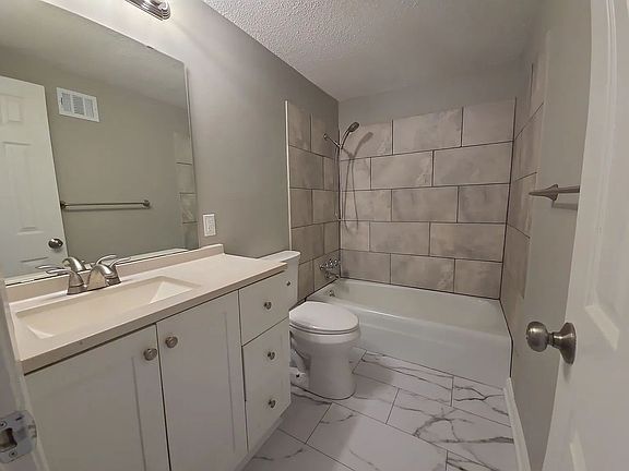 Full bath featuring tiled shower surround, updated vanity, and modern fixtures