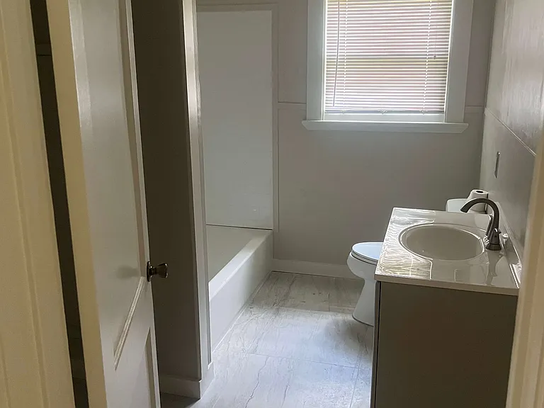 Newly remodeled bathroom with white countertops and new flooring