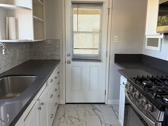 Kitchen with Luxury Plank tiles, Stainless steel refrigerator, microwave and stove. Dishwasher and built in desk. The back door leads to deckhand downstairs to Second Street.