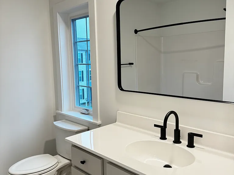 Full bathroom attached to accessory bedroom on third floor with a large mirror
