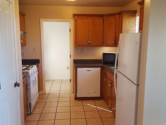Kitchen view with stove, dishwasher and refridgerator. Laundry room past doorway. Closet pantry to the left.