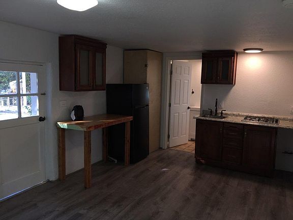 Special lighting above gas stove and a sink area. Small refrigerator and high solid wooden table.