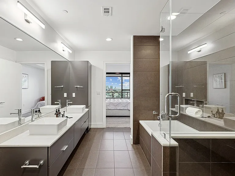 Spa-like, Modern Bathroom with Dual-Sink Vanity, Glass Enclosed Shower, and Soaking Tub.