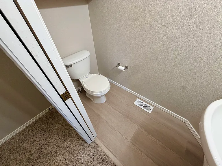2nd view of convenient main-level half bath with new LVP flooring installed 6/5/2026, and pocket door for improved flow and privacy.