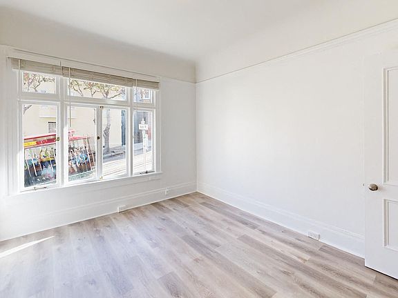 Sunlit room with a large window and a wood-like flooring