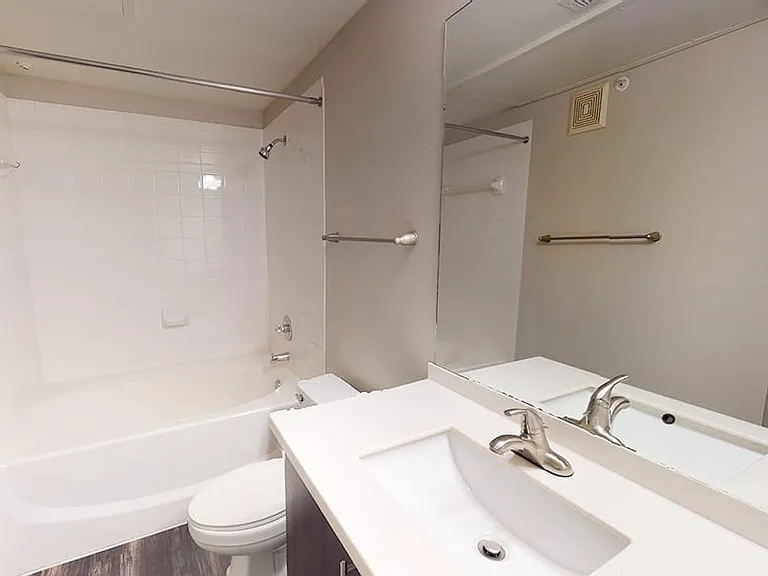 Apartment bathroom with large soaking tub and wood-style flooring.