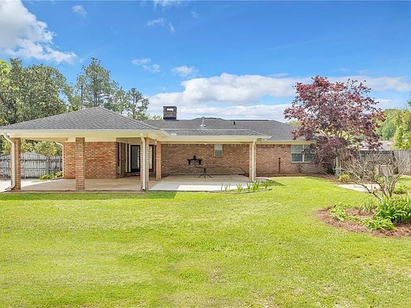 Rear view of house featuring a patio, a chimney, and brick siding