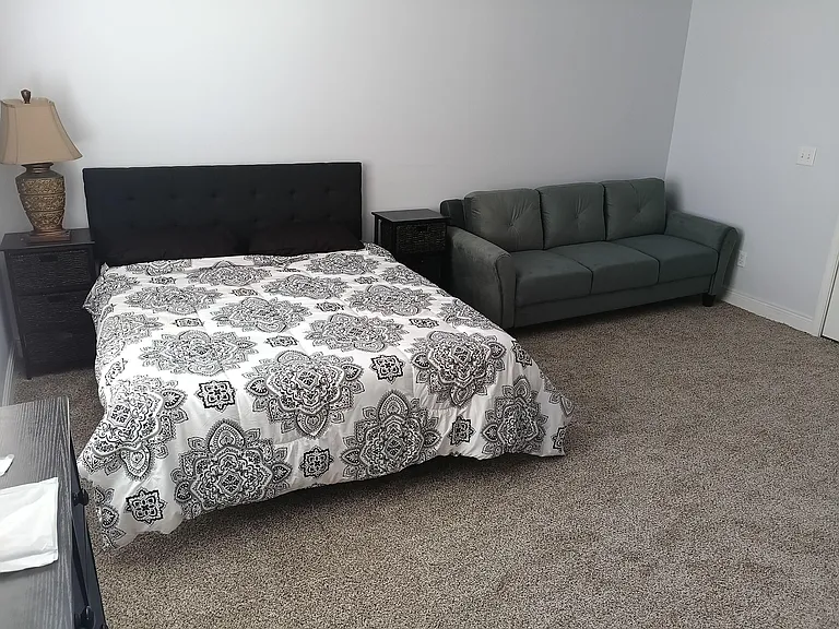 Furnished bedroom with a full bed, nightstands, and a sofaideal for relaxing or studying in your own space.