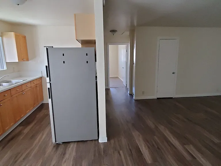 Looking down hallway to bedrooms and kitchen with wood stained cabinets and window at Zenith Place Apartments in Chula Vista, California.