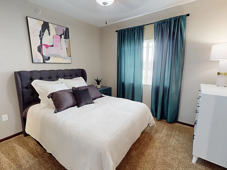 The primary bedroom in The Hub floor plan features lush carpet, a large window, and en suite bathroom.