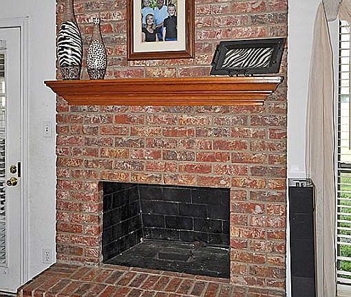 Fireplace with brick hearth and wood mantel.