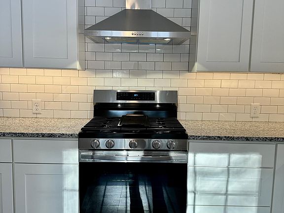 Gas range with hood, subway tile, granite counter and new cabinetry with soft close doors and drawers