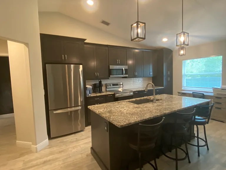Kitchen - Stainless steel appliances, tile floor, recessed lighting, hanging light fixtures over breakfast bar, granite counter tops, eat-in area