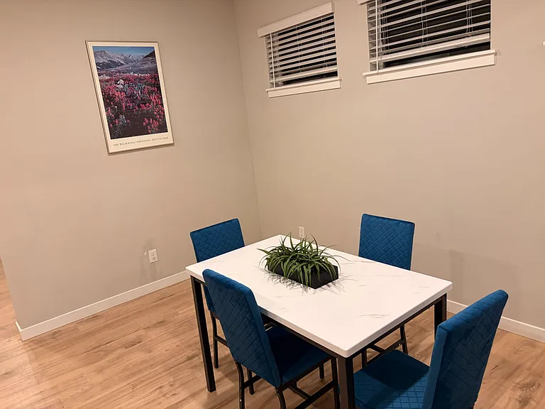 Dedicated dining area with a full-size table, comfortable seating, and nearby windows with blinds for natural light.