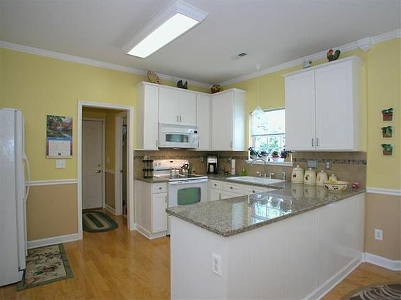 Remodeled kitchen with granite counters, bead-board cabinets, tile backsplash