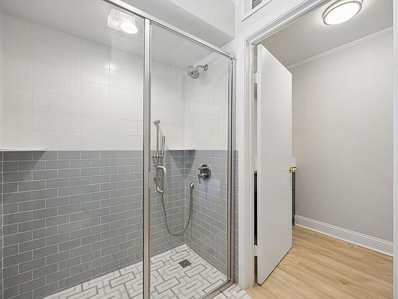 Primary bath with a glass-enclosed shower featuring dual shower heads and a clean, modern finish.