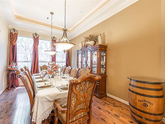 Formal dining room w/ stunning wood flooring & triple crown molding tray ceiling w/ lighting on a dimmer switch.