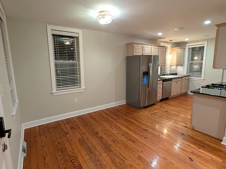 looking from the front door toward the kitchen. The kitchen has recessed ceiling lights and under counter lighting.