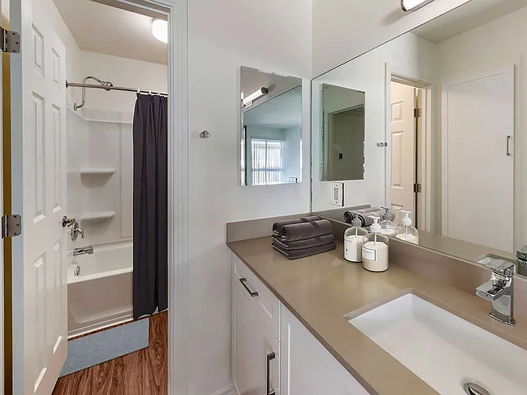 Renovated Package I bath with beige quartz countertops, new white cabinetry, and hard surface flooring