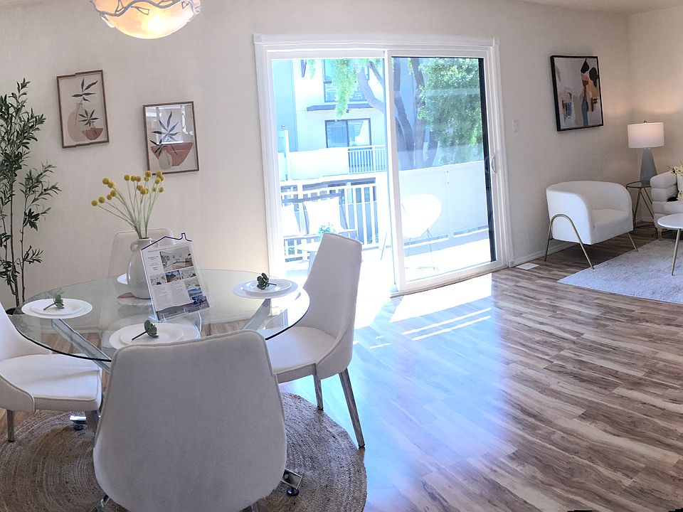 The living and dining area features designer mirrors that reflect natural surroundings and enhance the sense of space. A glass door opens to the balcony, inviting in abundant natural light and fresh air.