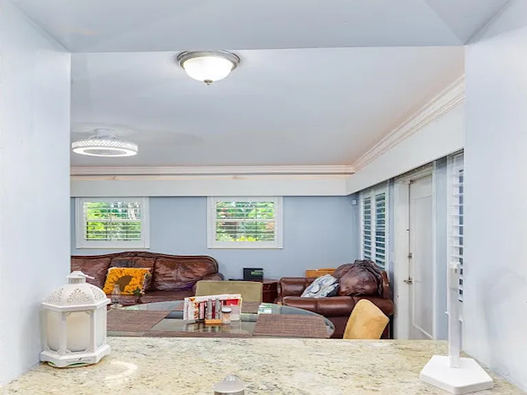 Open living area with seating for relaxing and large windows with shutters, plus a pass-through counter for serving.