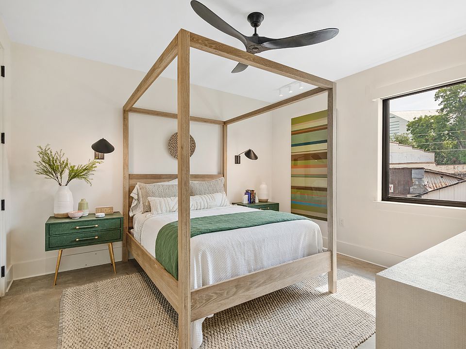 The bedroom features a modern four-poster bed, original art, and luxury furniture.
