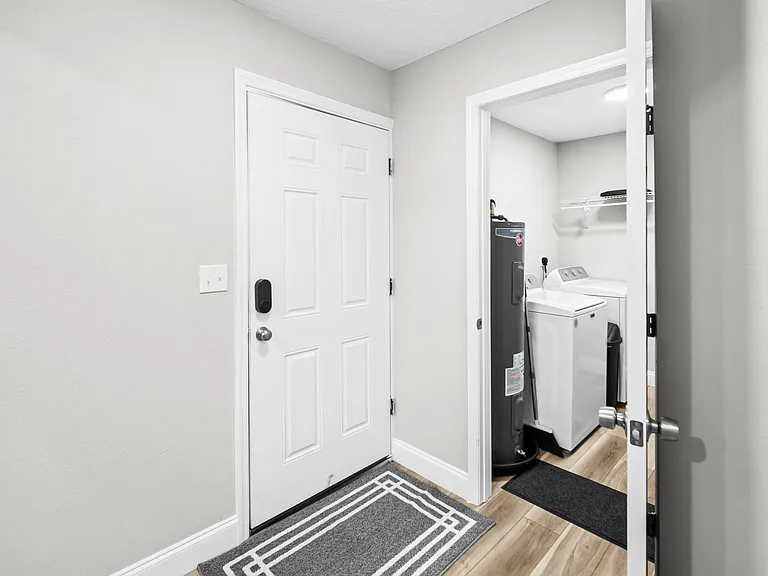 Convenient laundry nook with washer/dryer hookups, storage shelf, and adjacent utility space off the main entry.