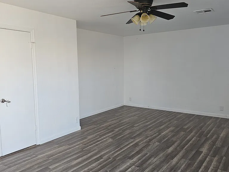 Spacious primary bedroom featuring updated flooring, ceiling fan, and dual door access, creating a bright and functional layout for comfort and convenience.