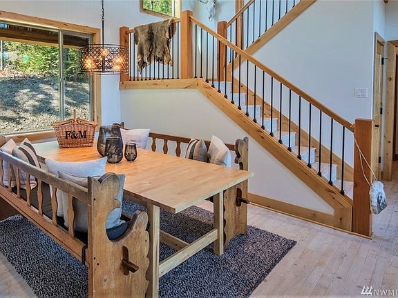 The dining room is a perfect space for comfortable meal sharing and game nights. The stairwell leads to three bedrooms on the upper level, one of which is an en-suite.