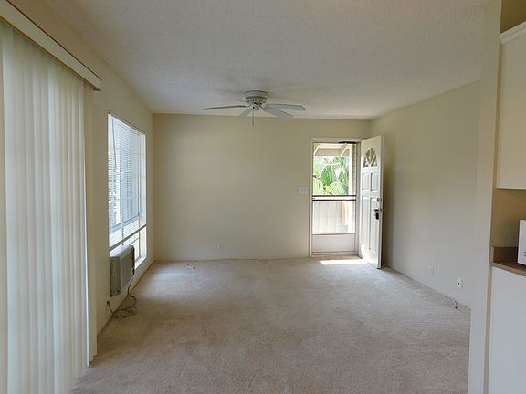 View from the dining area toward the living area and front door. Screen door for added ventilation. Ceiling fan and window A/C.