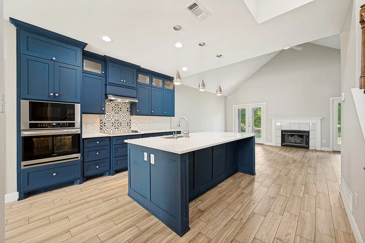 Contemporary kitchen featuring deep blue cabinetry, stainless steel appliances, and a central island with a white countertop - 9426 Abbey Rd