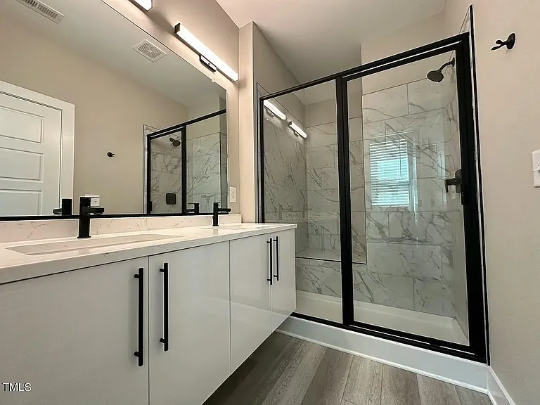 Primary luxury bath with tiled shower with seat and double sinks with quartz counter tops.