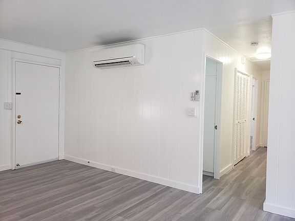 Front door/living room with split AC unit, first door on the right is guest bathroom, 2nd door is master bathroom. Storage closet and additional storage at end of hall.