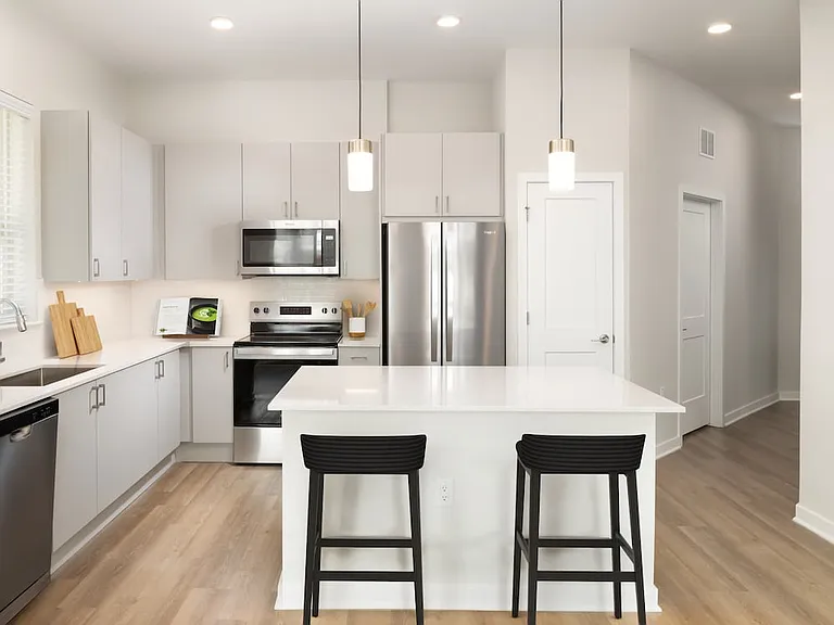 Base Collection kitchen with stainless steel appliances, white quartz countertops, white tile backsplash, grey cabinetry, and hard surface flooring