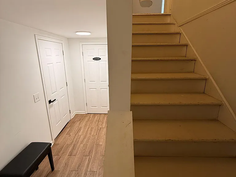 Lower-level hallway with stair access, durable flooring, and nearby laundry/utility storage for daily convenience.