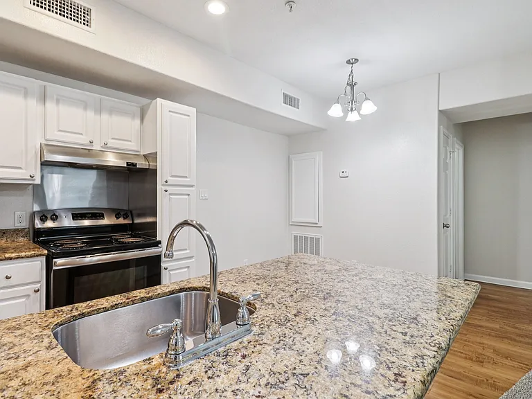 Modern kitchen with granite countertops, sleek stainless steel appliances, and elegant lighting fixtures, offering a warm and inviting atmosphere. Modern kitchen with granite countertops, sleek stainless steel appliances, and elegant lighting fixtures, of